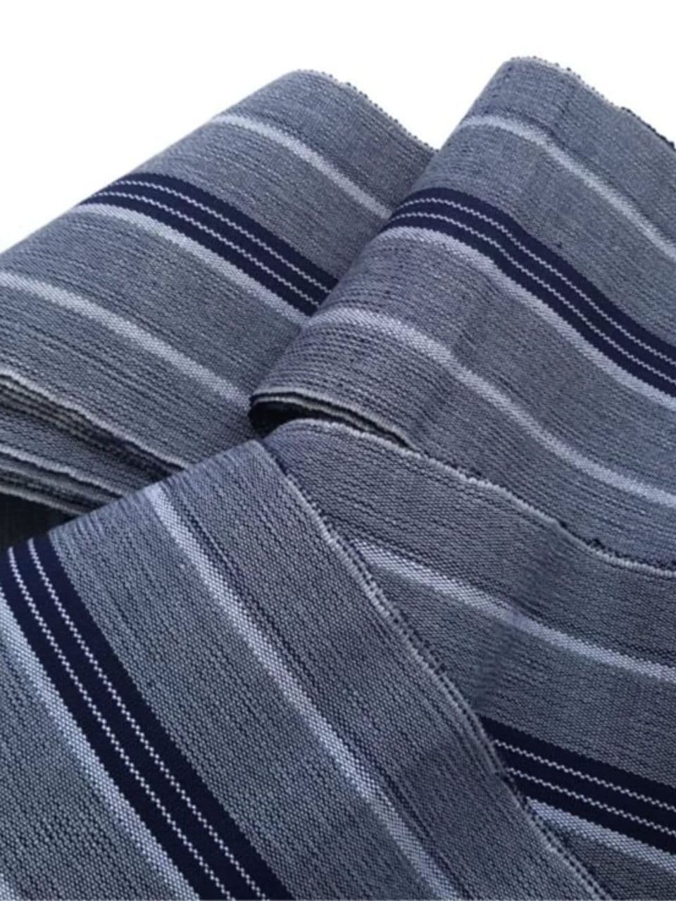 Folded grey woven textile with navy blue and white horizontal stripes of various widths.