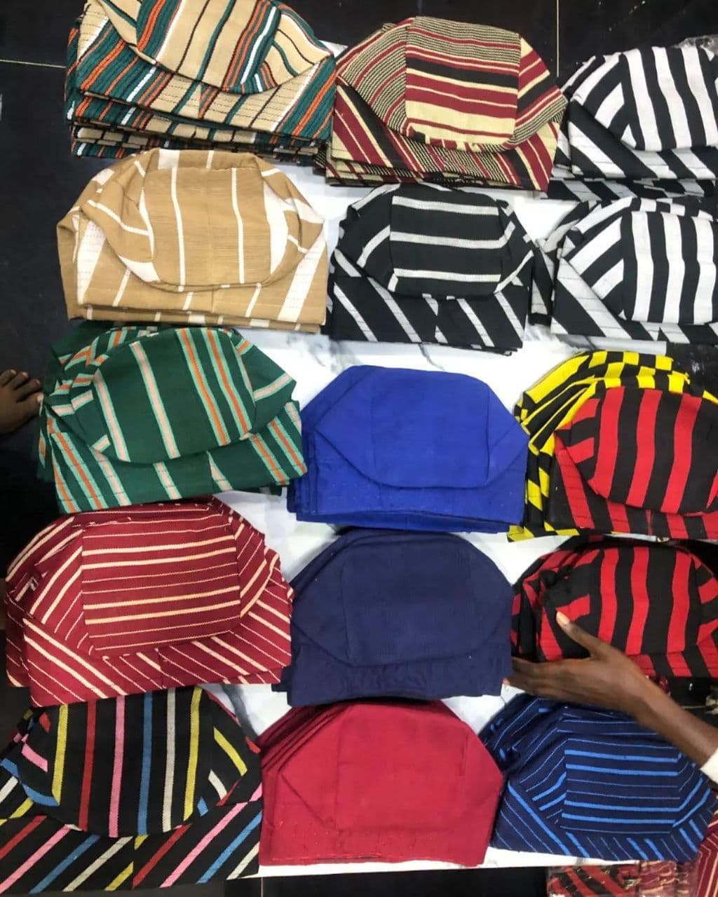 Neatly arranged rows of colorful, striped and solid traditional West African fila caps.
